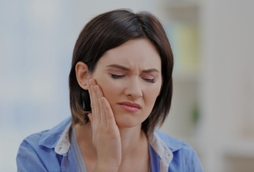 Woman in need of T M J therapy holding jaw in pain