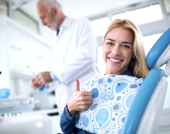 Woman in dentist’s chair giving thumbs up